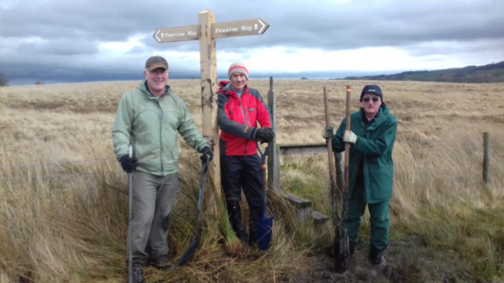 three volunteers install a fingerpost on the Pennine Way