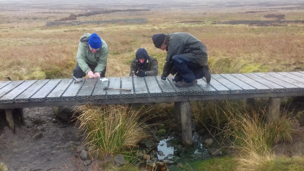 three volunteers fix a boardwalk on the Pennine Way