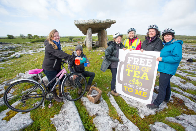 cycling group pose for tea in front of dolmen on limestone pavement